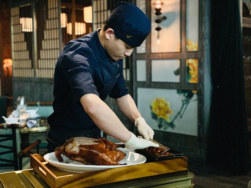 A young chef skillfully carves roast duck on a plate indoors, showcasing his culinary expertise